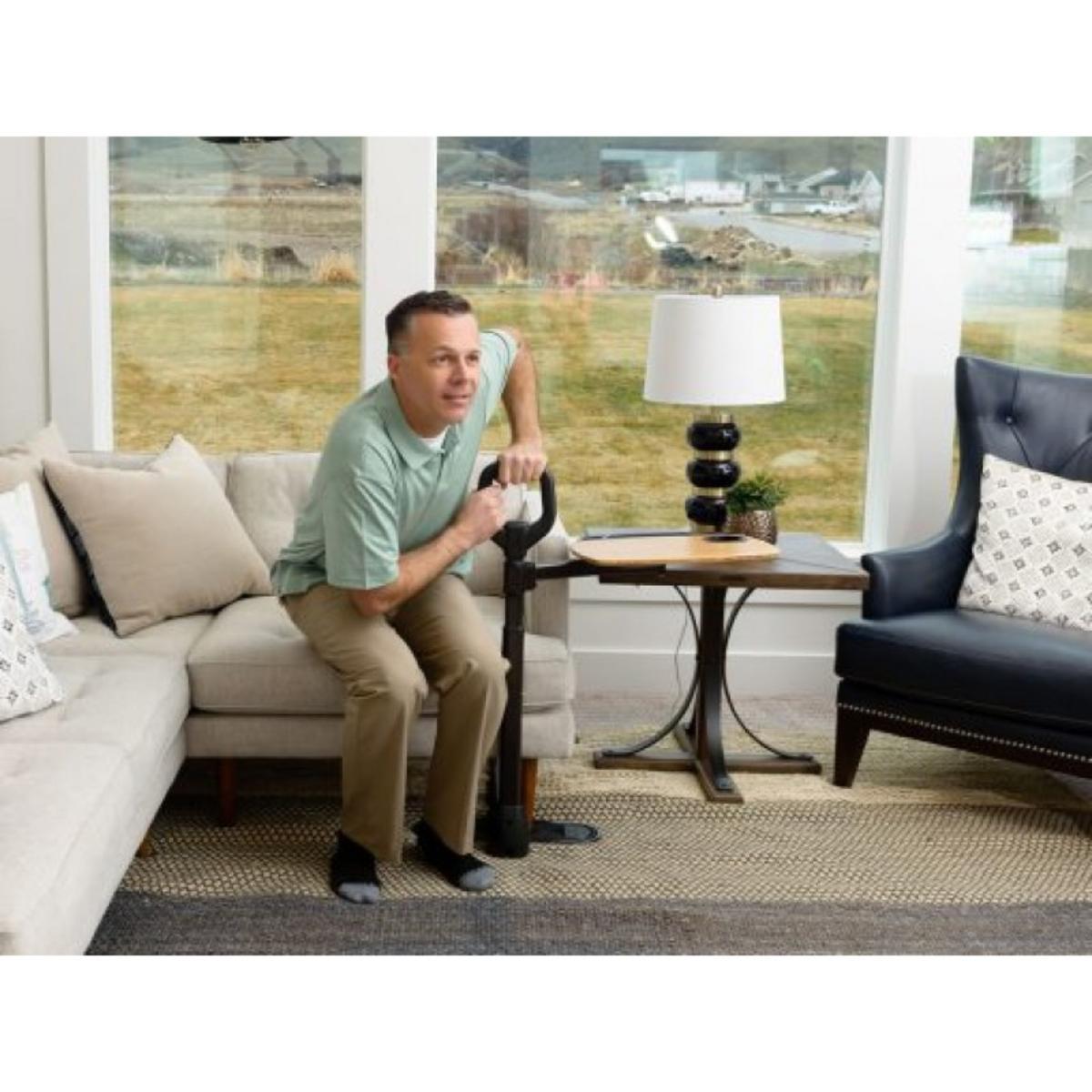 Man sitting on a couch in a living room with a view of a field.