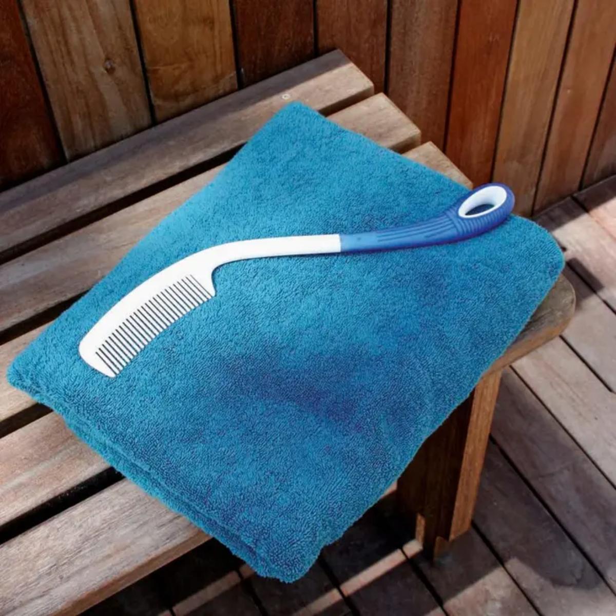 Blue towel with a white comb and blue handle on a wooden surface