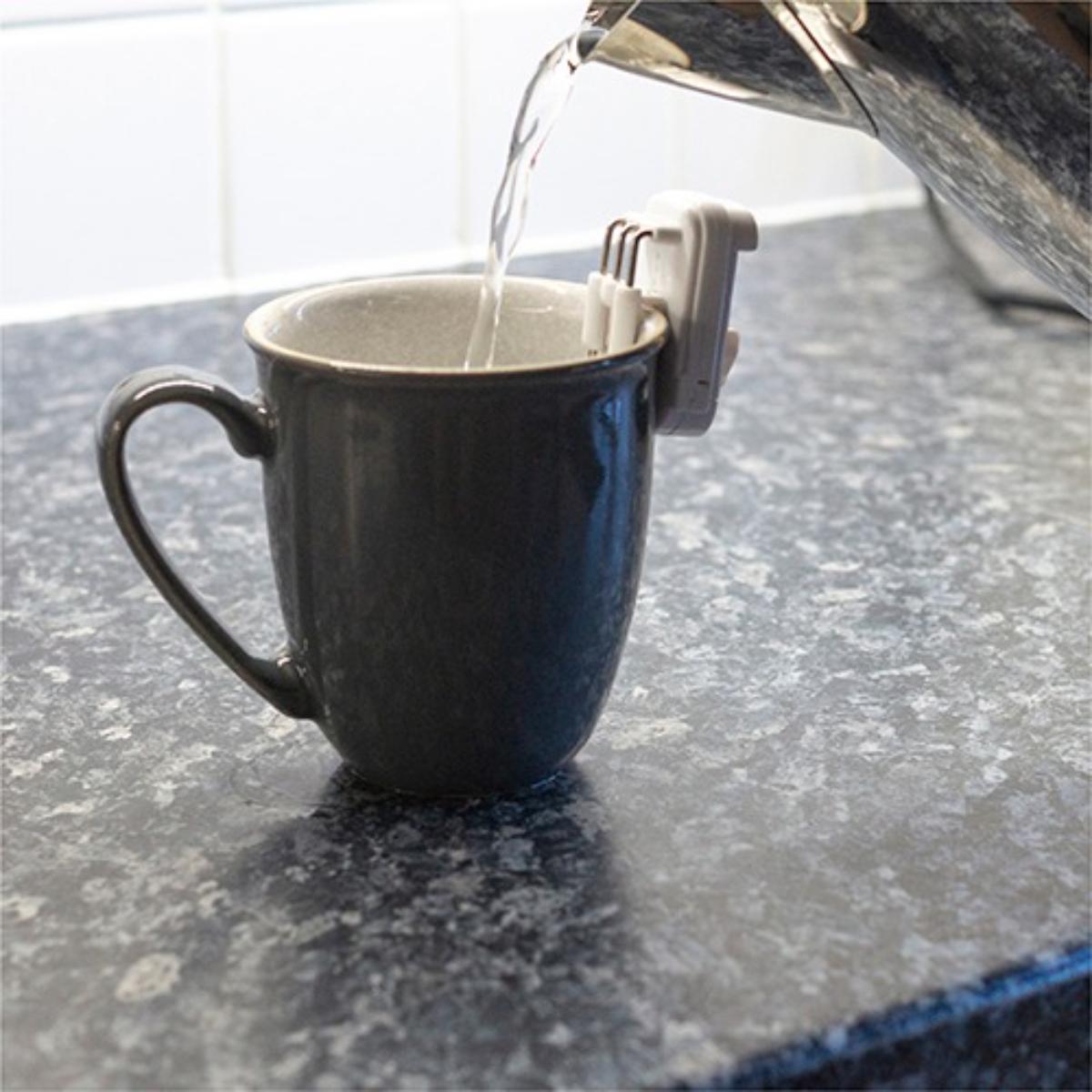Black mug being filled with water from a faucet on a gray countertop.